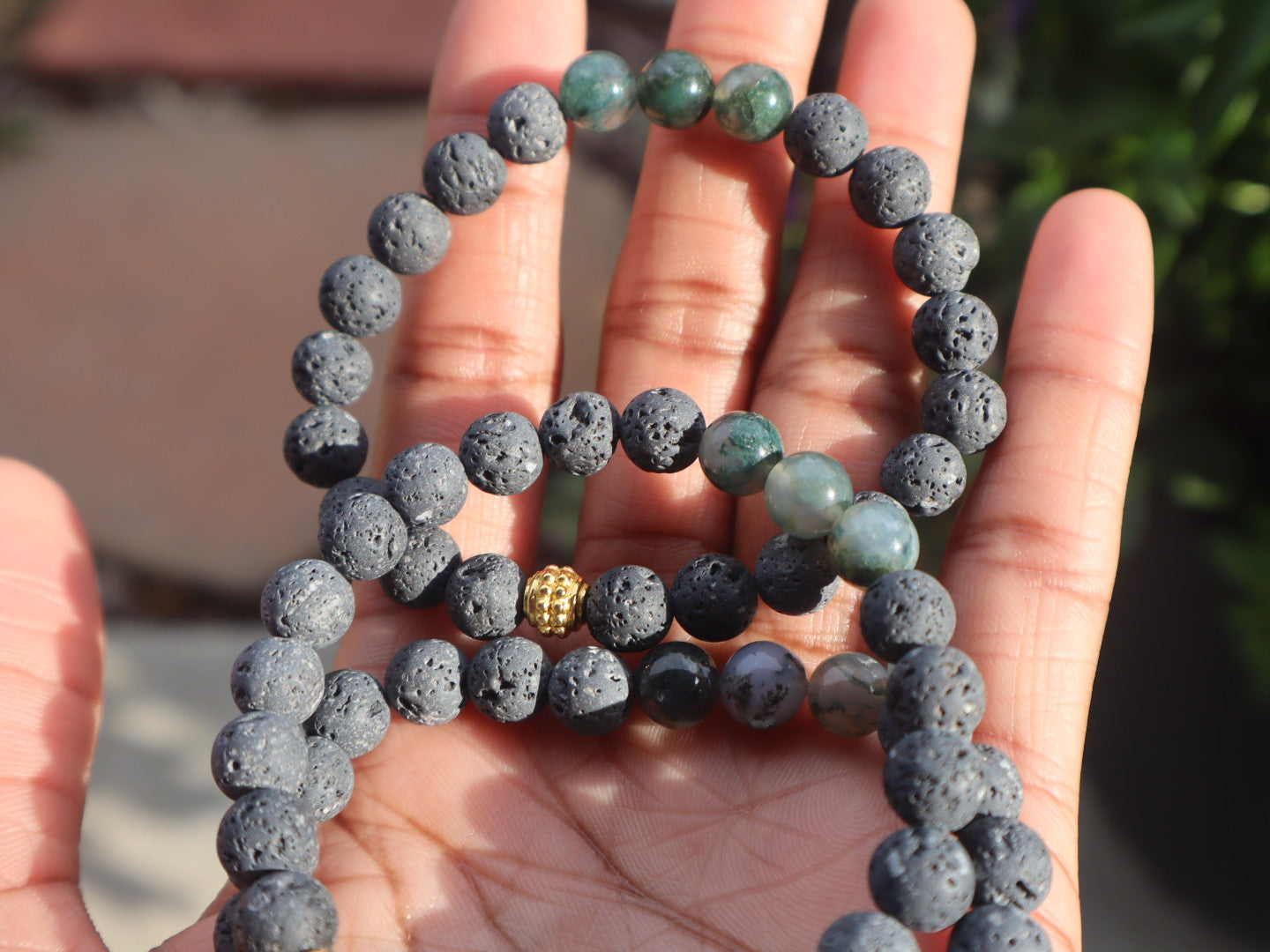 Hand holding a bracelet with blue and green beaded design