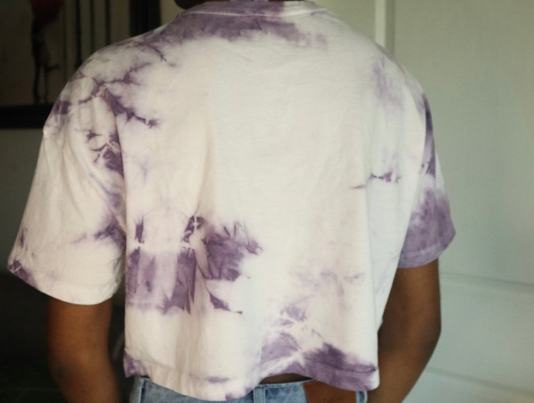 Person wearing a tie-dye shirt with purple and white patterns.