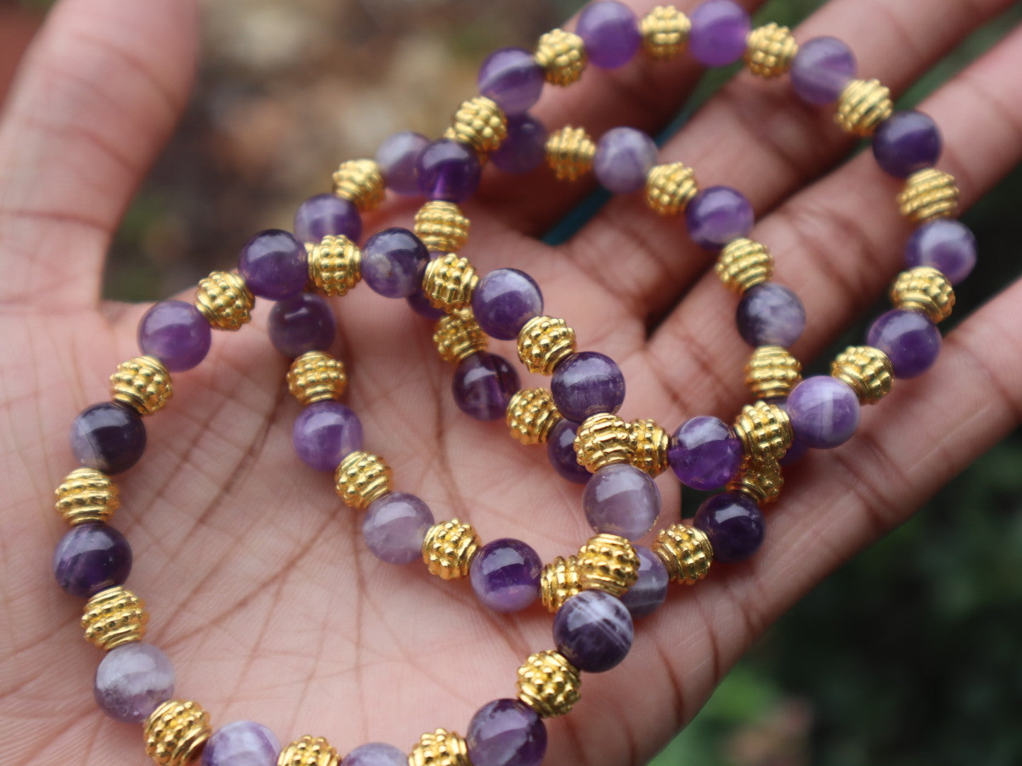 Purple beaded bracelet with gold accents on a hand