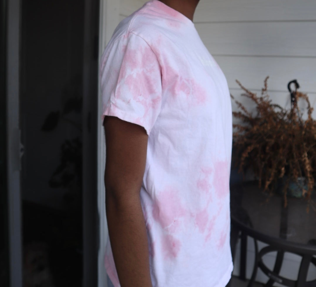 Person wearing a pink and white tie-dye shirt outdoors.
