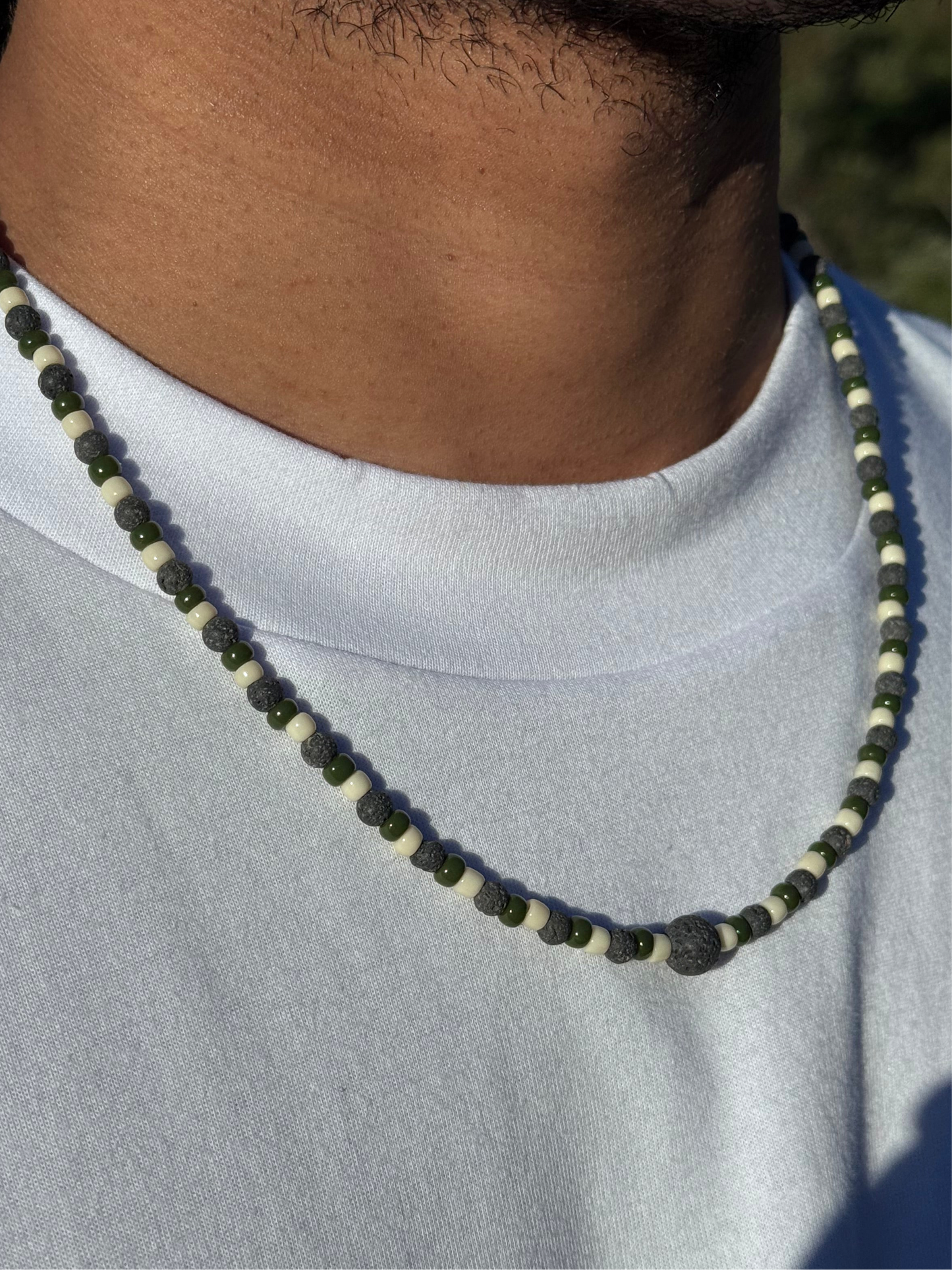 Necklace with green beads worn by a person against a neutral background