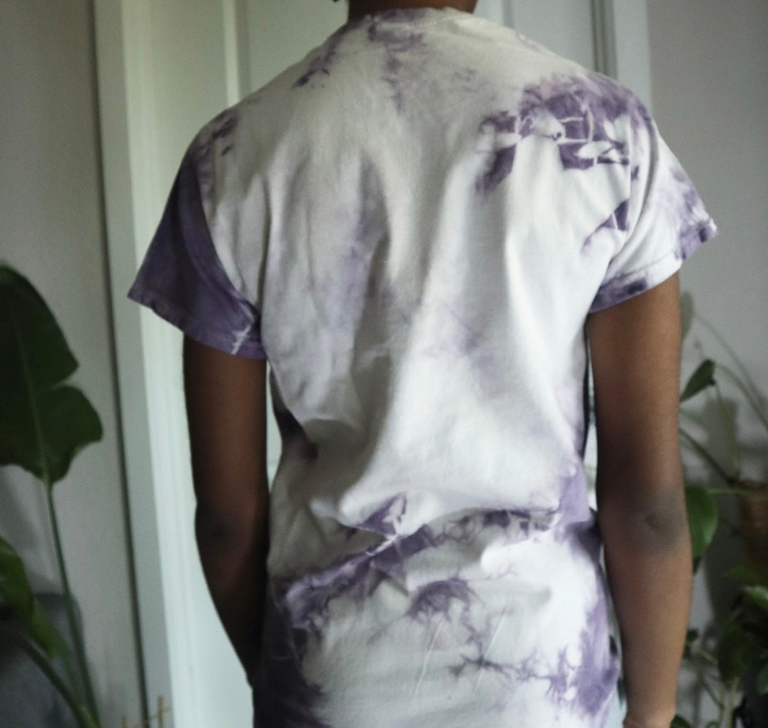 Person wearing a white and purple tie-dye shirt in a minimal indoor setting