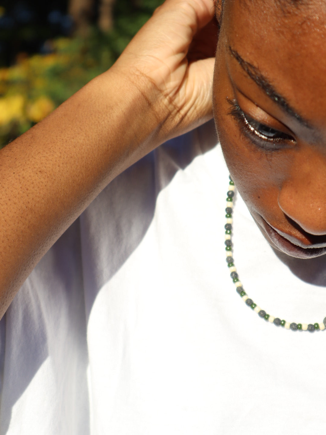 Close-up of a person putting on a lava rock necklace.