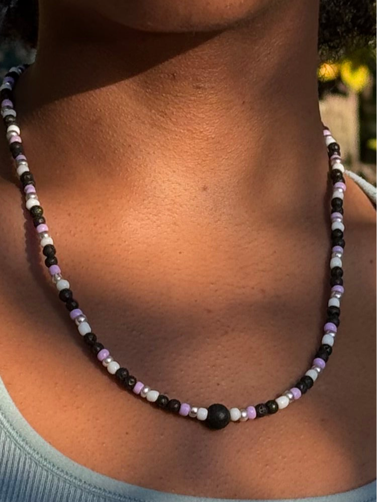 Necklace with black, white, and purple beads on a person's neck.