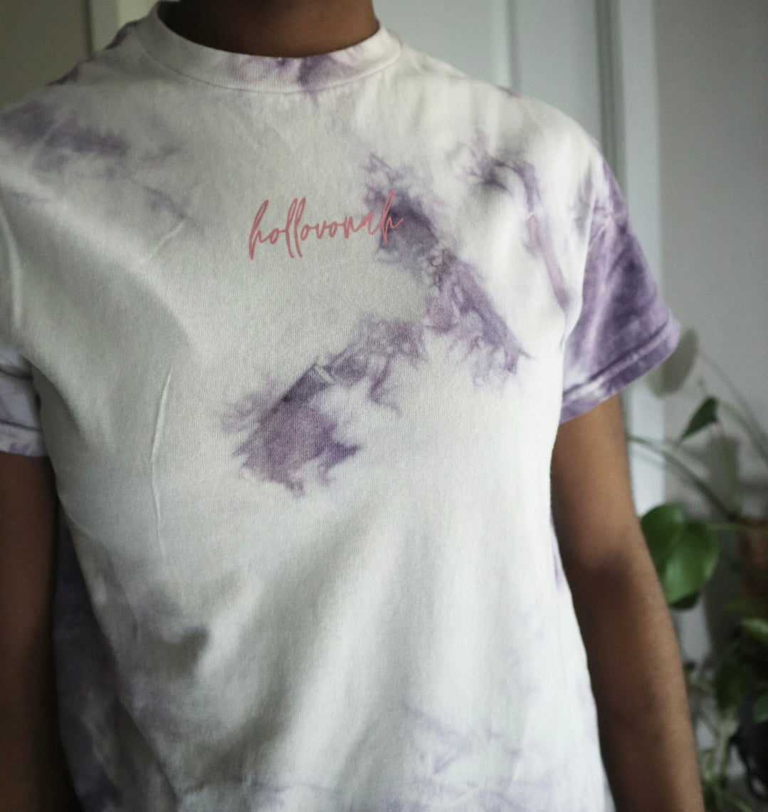 Person wearing a tie-dye t-shirt with pink 'hollovonah' text.