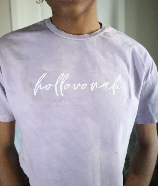 Person wearing a light purple t-shirt with 'hollovonah' printed on it.
