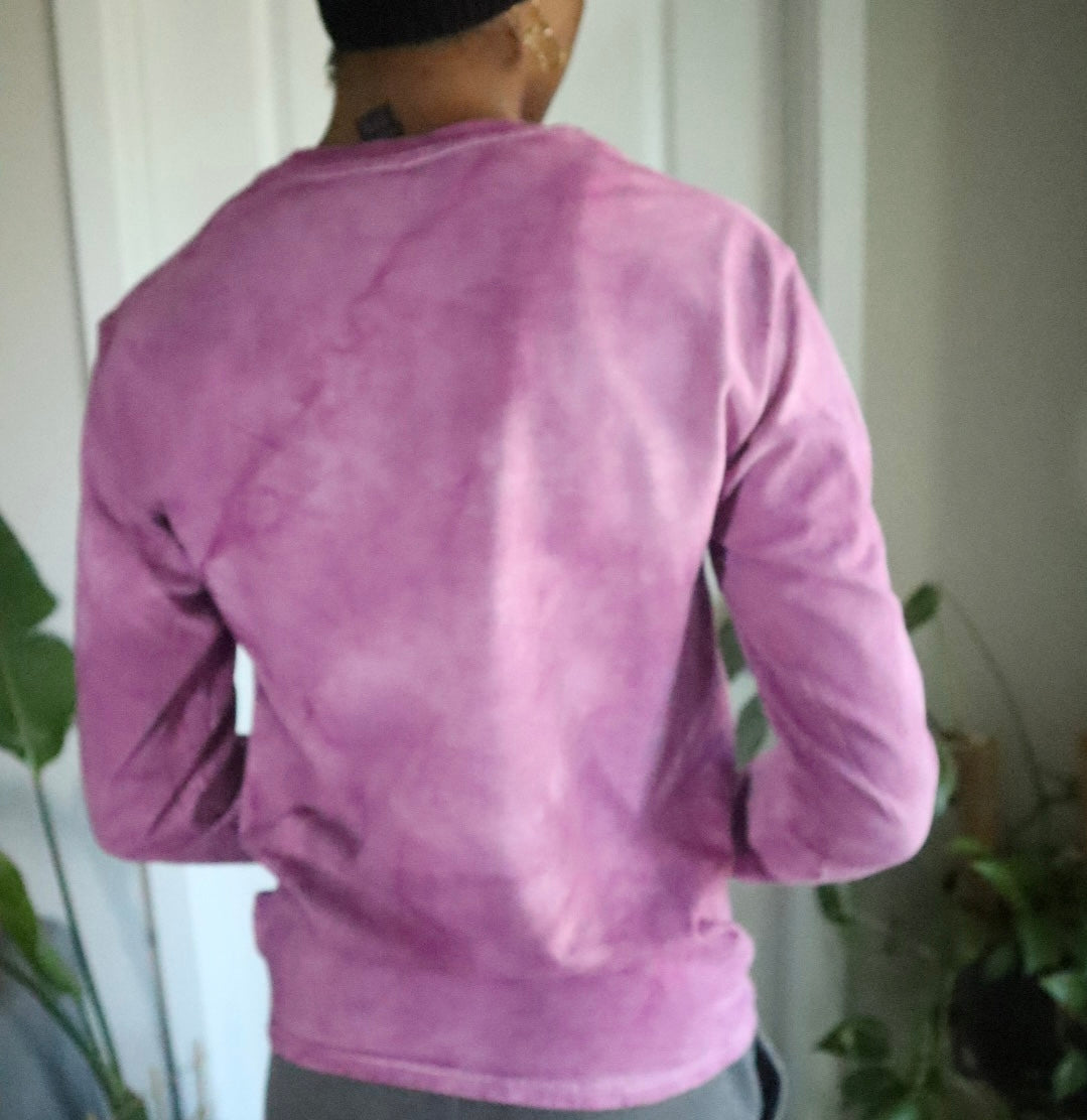 Person wearing a purple long-sleeve shirt with a neutral background