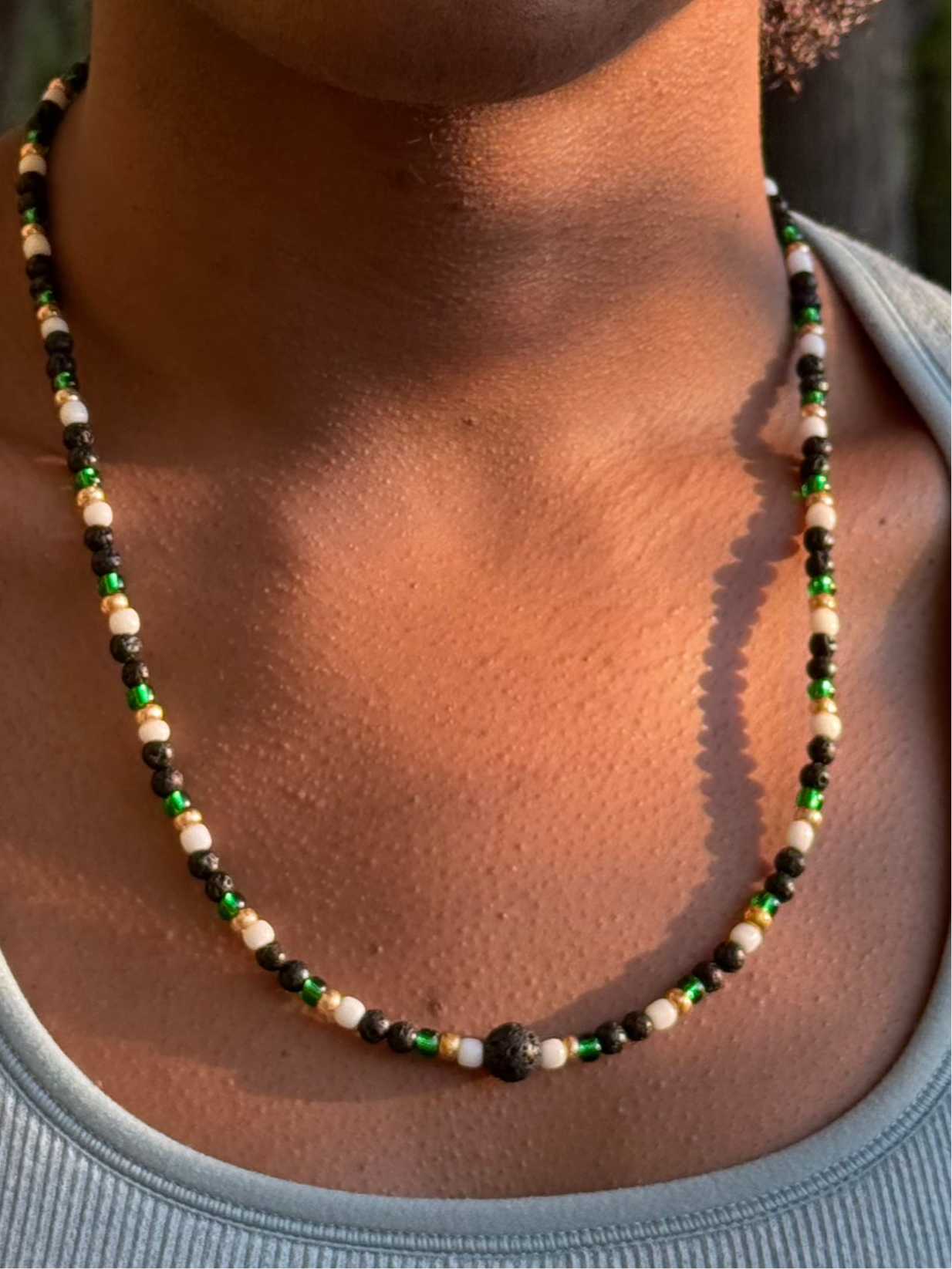Necklace with multicolored beads on a person wearing a light gray top.