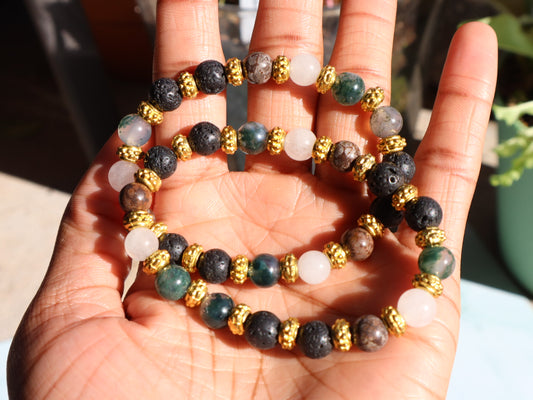Hand holding a stack of beaded bracelets with gold accents