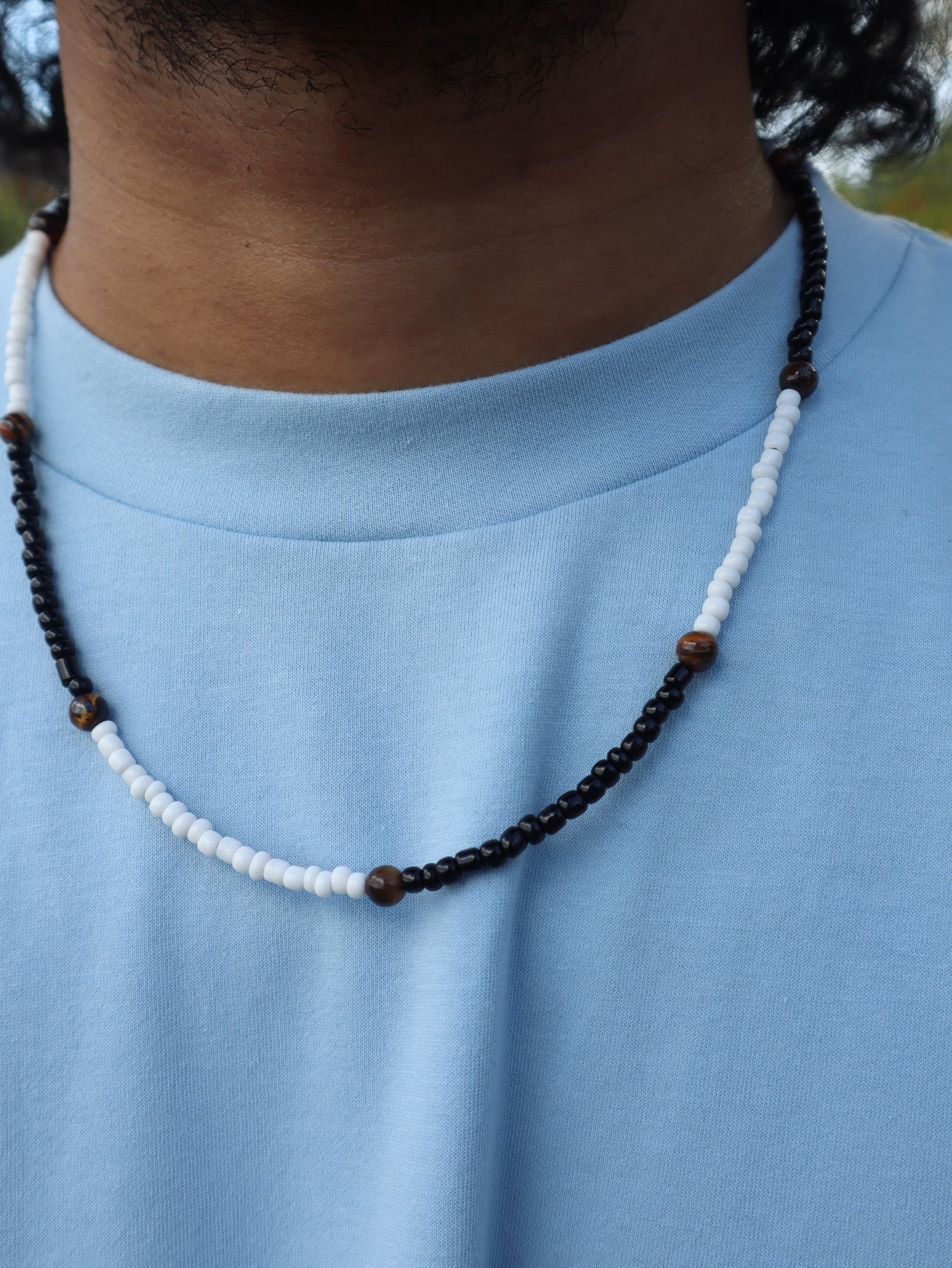 Beaded necklace with brown and white beads on a blue fabric background