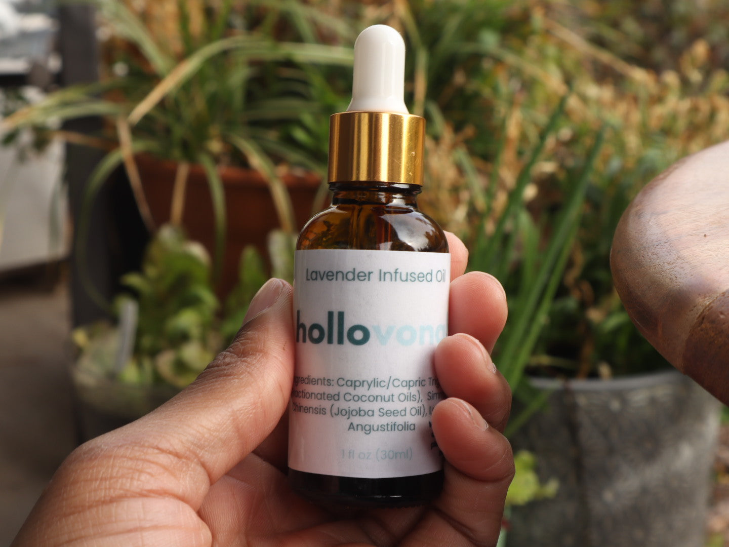 Bottle of lavender infused oil with dropper held in hand against a natural background