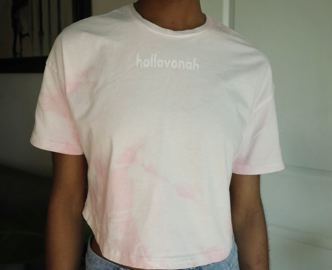 Person wearing a tie-dye t-shirt with 'hollovonah' text in a casual setting