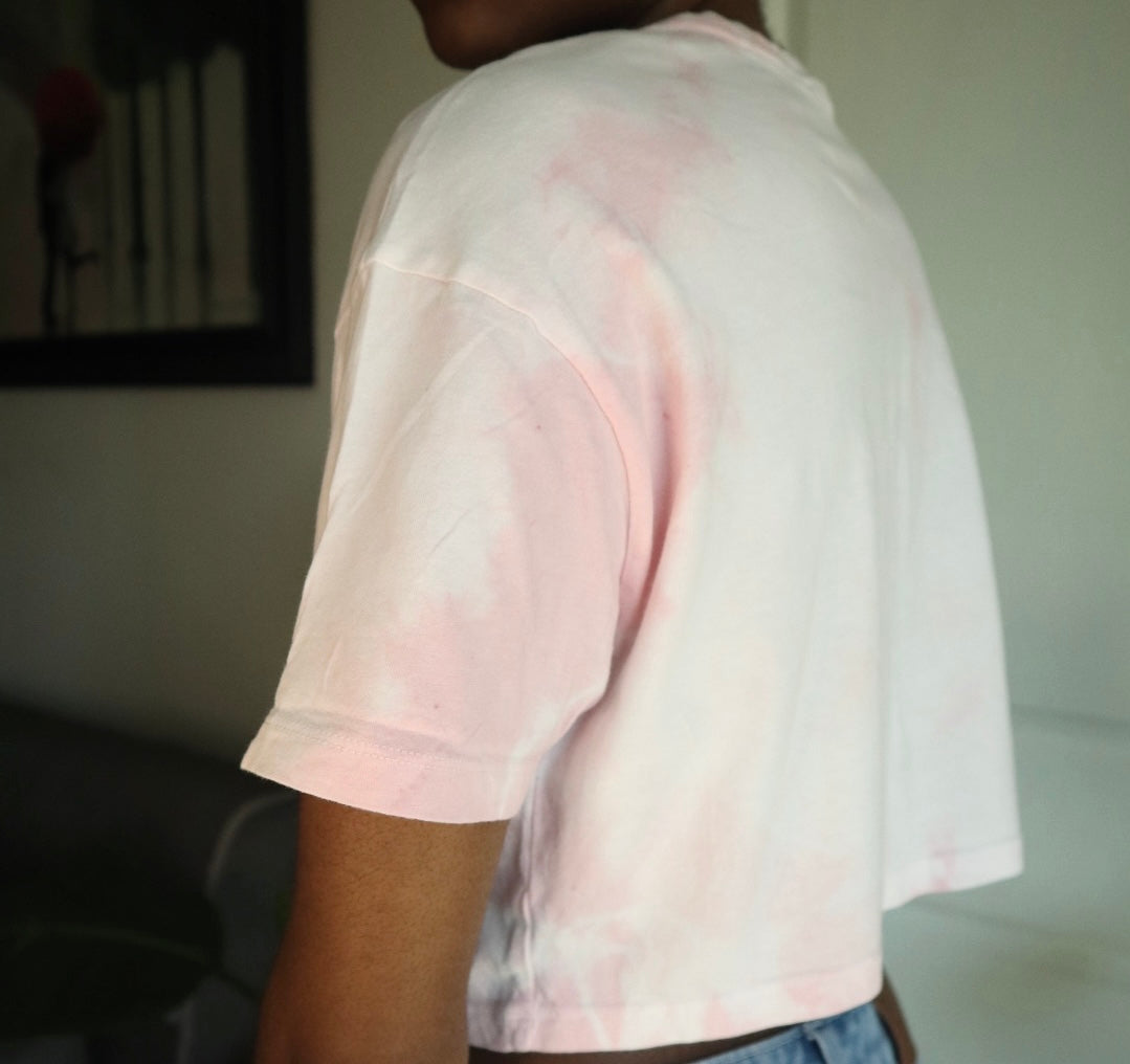 Person wearing a light pink tie-dye t-shirt in an indoor setting