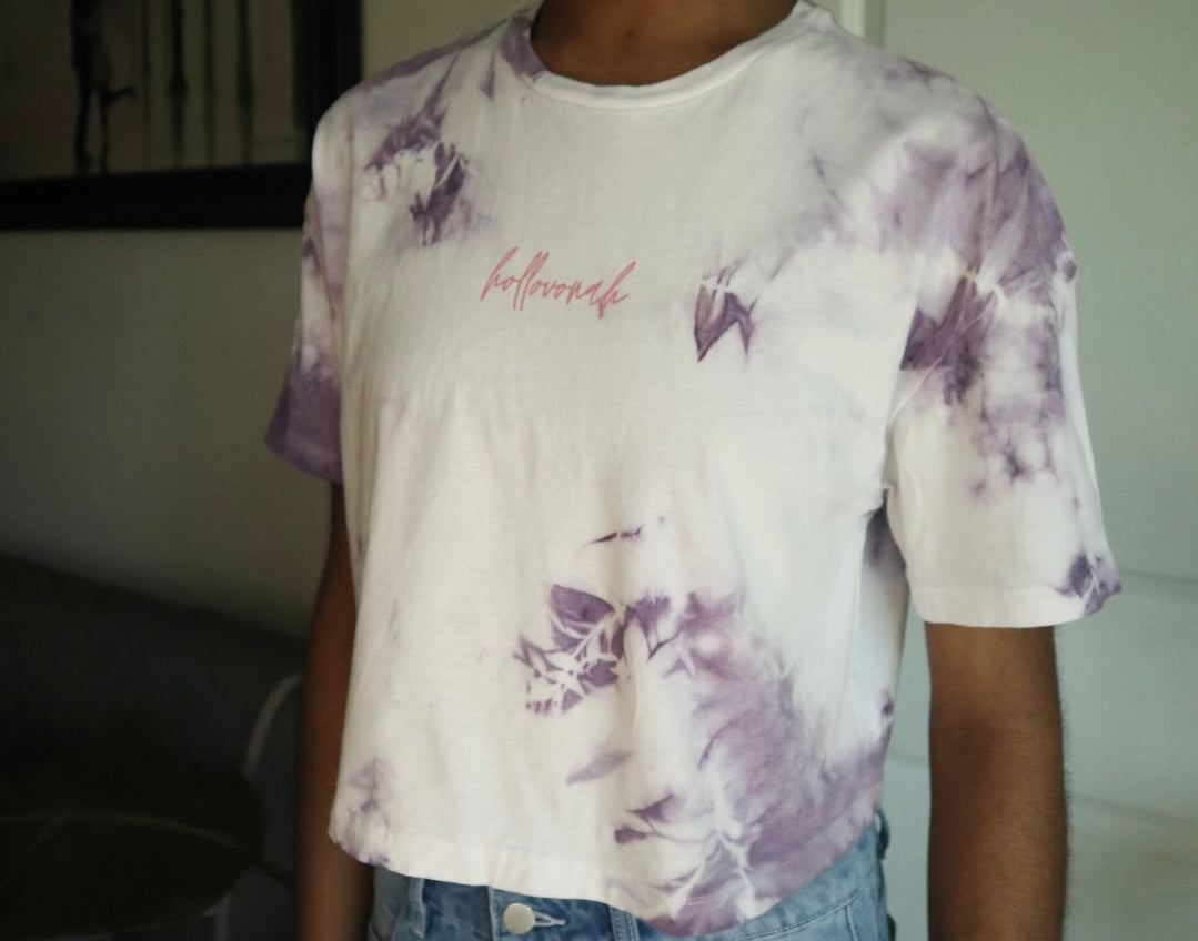 Person wearing a white t-shirt with purple floral patterns and text.