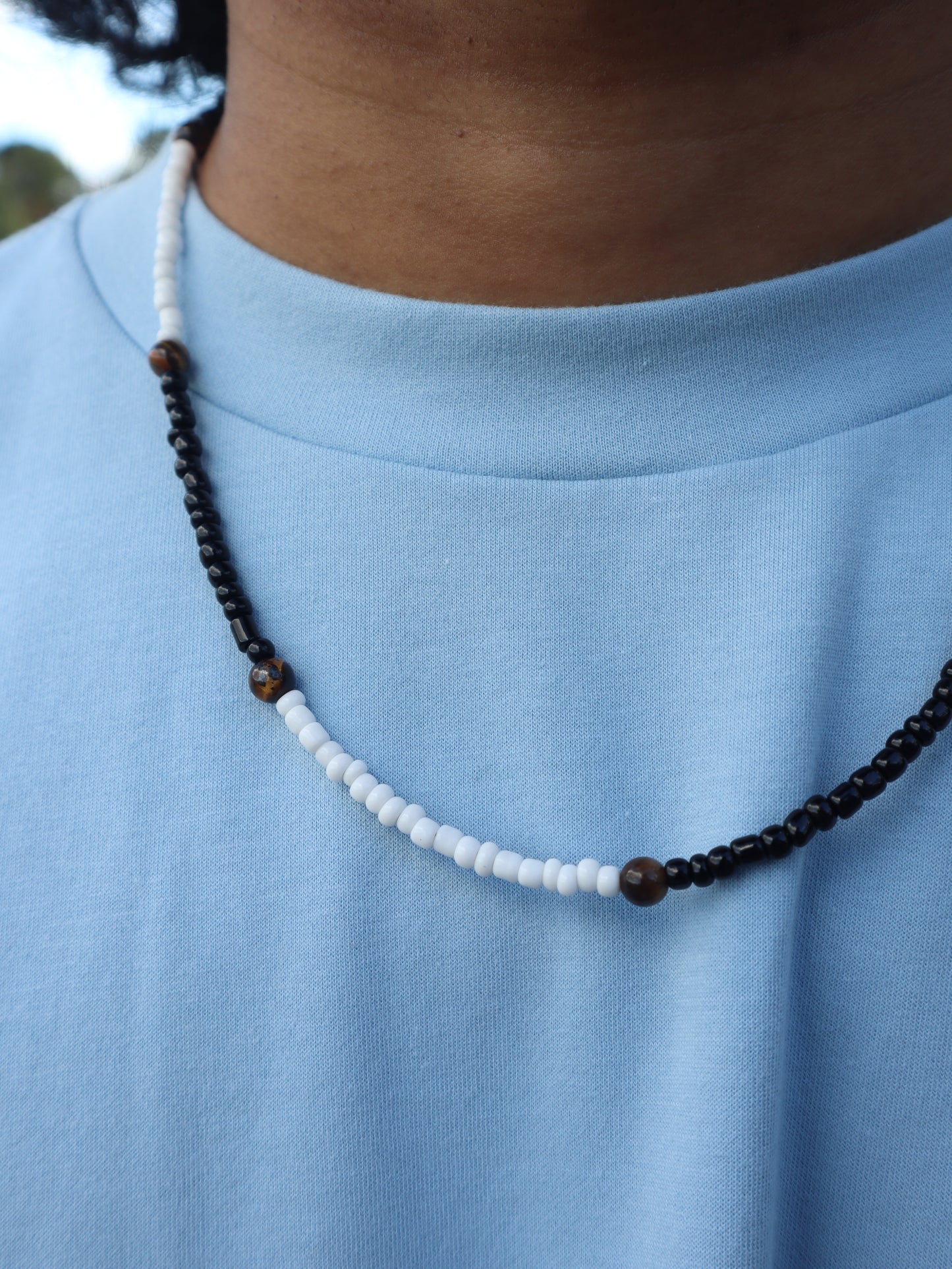 Beaded necklace with black and white beads on a blue fabric background