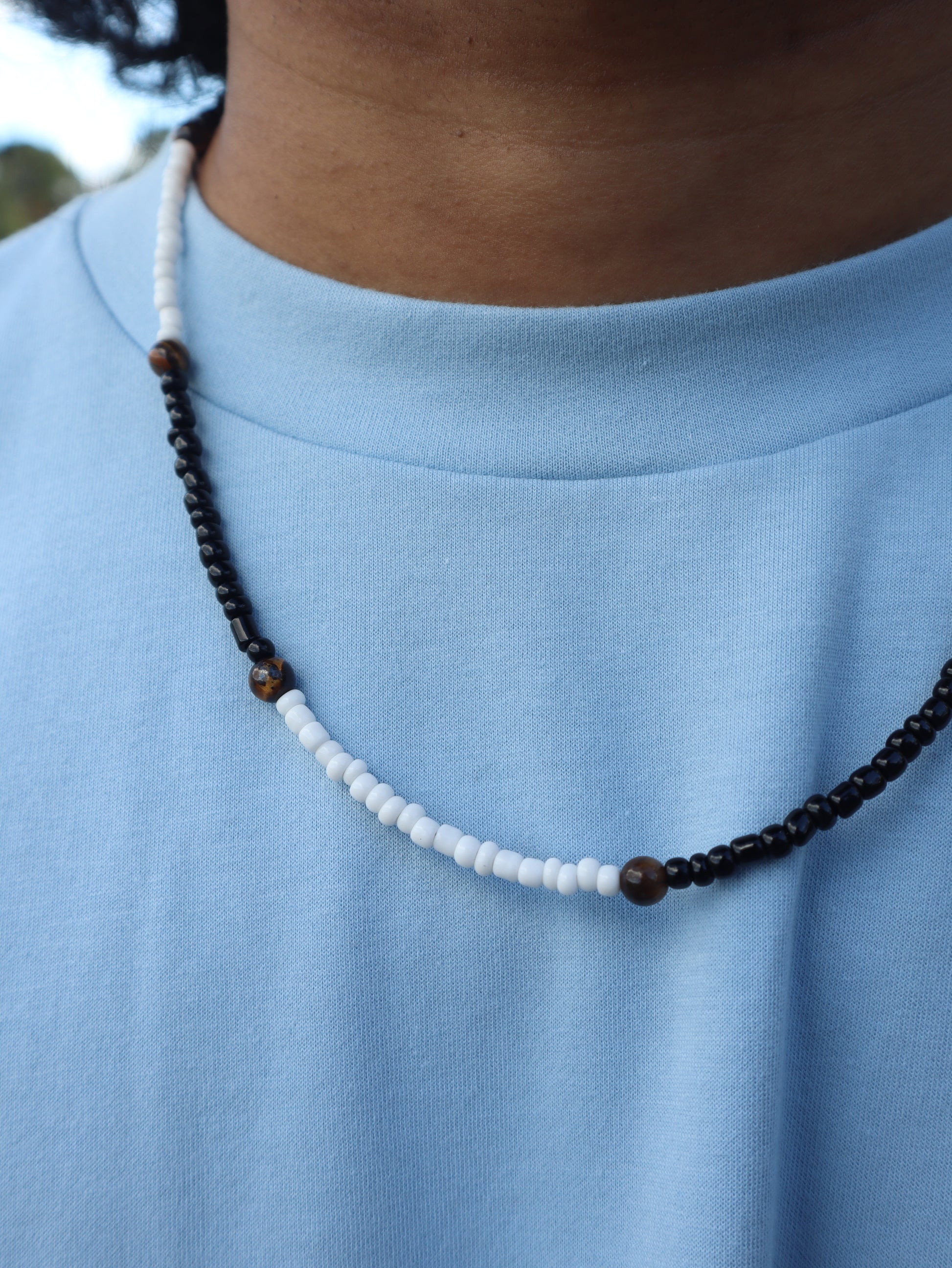 Beaded necklace with black and white beads on a blue fabric background